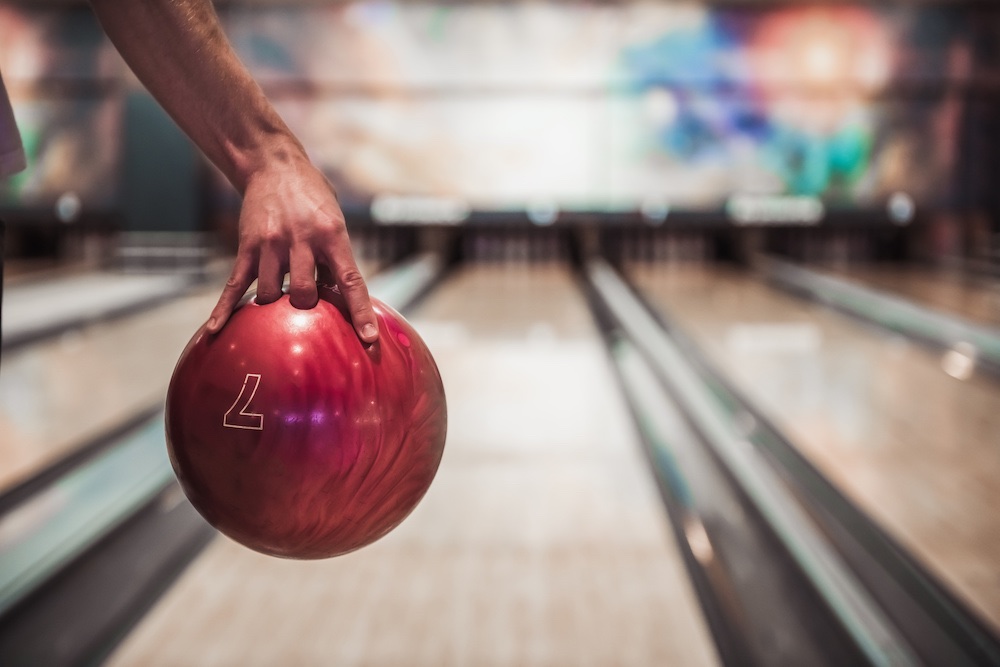 Bild på en man som ska skjuta iväg en bowlingkula på en bana